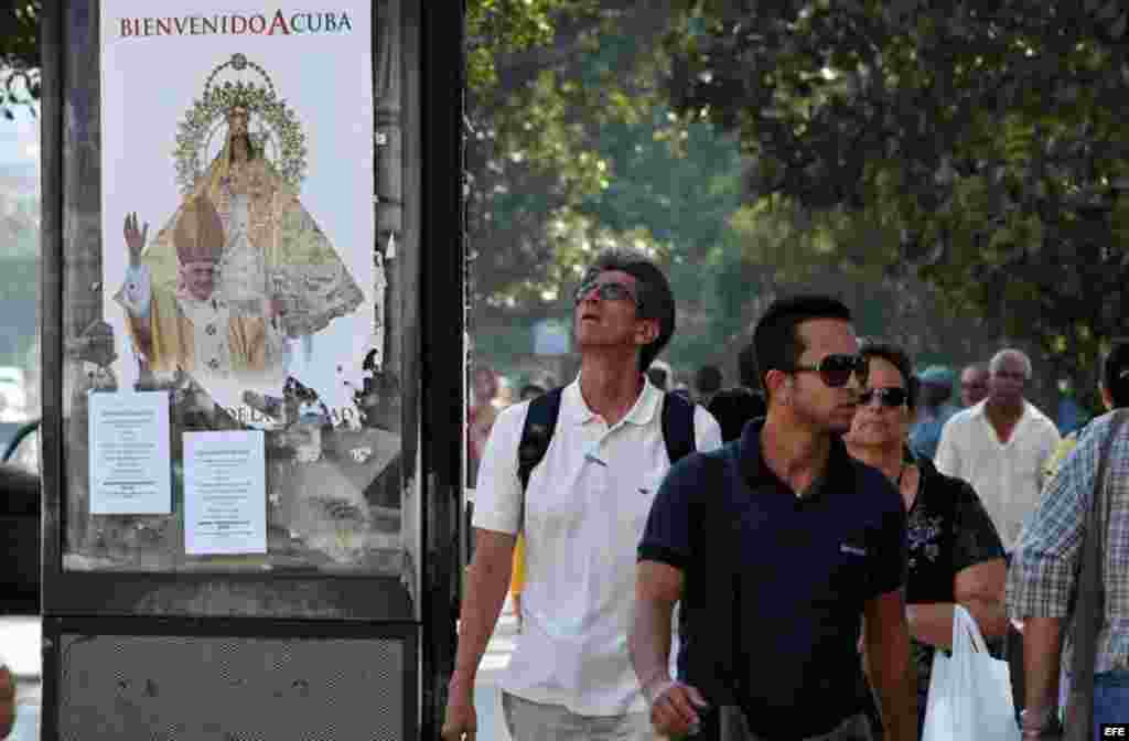 Transeúntes caminan frente a un cartel de bienvenida al papa Benedicto XVI hoy, lunes 19 de marzo, en La Habana (Cuba). El Pontífice llegará a la isla el próximo día 26 para una visita de tres días. EFE/Alejandro Ernesto